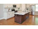 Modern kitchen boasts white cabinetry, stainless appliances, and granite countertops, complemented by hardwood flooring at 120 Glen Oaks Dr, Youngsville, NC 27596