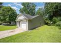 View of the backyard with green grass and a detached single car garage with driveway at 125 Brook Pl, Smithfield, NC 27577