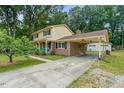 Two-story home with yellow siding, brick accents, a covered carport, and a long driveway at 1704 Little John Ct, Burlington, NC 27217