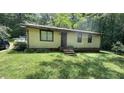 Small, yellow single-story house with a brick stair entrance and wooded surroundings at 181 Mangums Dr, Wendell, NC 27591