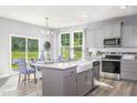 Modern kitchen with stainless steel appliances, large island with sink, and open access to dining area at 219 Faith Avenue, Sanford, NC 27330