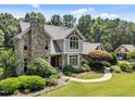 An elevated view of a well-maintained home with stone accents, lush greenery, and a circular driveway at 267 Bald Eagle Dr, Pittsboro, NC 27312