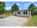 Charming renovated home with gravel drive, white painted brick, black roof and trim and lovely yard at 311 Troy St, Creedmoor, NC 27522