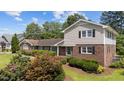 Charming brick home boasts a well-maintained lawn, complemented by mature landscaping and black window shutters at 315 Crescent Dr, Clayton, NC 27520