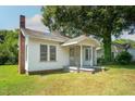 Side view of a one-story home with a brick chimney and a covered front porch, set on a grassy lot at 402 Poplar St, Graham, NC 27253