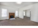 Spacious living room with a brick fireplace, carpeted floors, and ample natural light from large windows at 402 Poplar St, Graham, NC 27253