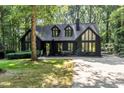 Charming exterior view of the home featuring large windows, a dark facade and mature trees at 5217 West Oaks Dr, Fuquay Varina, NC 27526