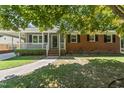 Inviting brick home showcasing a cozy front porch and well-maintained lawn at 908 Clarion Dr, Durham, NC 27705