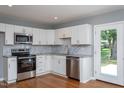 Updated kitchen featuring stainless steel appliances, white cabinetry, and beautiful hardwood flooring at 1344 Highland Dr, Wake Forest, NC 27587