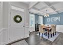 Elegant dining room with blue accent wall, coffered ceiling, and modern chandelier, adjacent to the home entrance at 175 Steep Rock Dr, Willow Springs, NC 27592