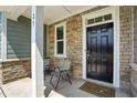 Inviting front porch with stone accents, seating, and a stylish black front door at 25 Harlow Ct, Fuquay Varina, NC 27526