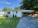 Lovely ranch-style home with a side carport and gravel driveway and landscaped shrubbery at 331 E Lillington St, Angier, NC 27501