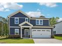 Inviting two-story home with navy siding, white trim, a two-car garage, and a well-manicured lawn at 3813 Rosebush Dr, Zebulon, NC 27597