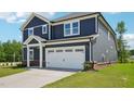 Side view of a navy two-story home featuring a two-car garage, neat landscaping and a blue sky at 3813 Rosebush Dr, Zebulon, NC 27597