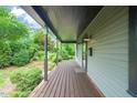 Inviting covered porch featuring dark wood floors and columns with lush greenery surrounding the space at 701 Holloway St, Durham, NC 27701