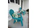 Inviting porch with Adirondack chairs, side table and colorful tropical cushions on a covered porch at 8 Open View Ln, Timberlake, NC 27583