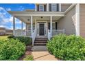 Inviting front porch with white railings and columns, steps leading to the front door, and lush landscaping at 86 Woodall Farm Ln, Princeton, NC 27569