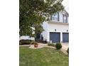 Home featuring a two-car garage, a manicured lawn with garden beds, and mature trees at 917 Widewaters Pkwy, Knightdale, NC 27545