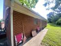 The exterior side of the brick house shows a well-maintained wall, tidy yard, and neatly arranged lawn chairs at 1021 Delray St, Durham, NC 27713