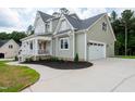View of the exterior featuring light green siding, a white garage door, and a covered front porch at 150 Purslane Dr, Franklinton, NC 27525