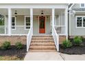 Close-up of the brick stairs and front porch with a orange entry door and white columns at 150 Purslane Dr, Franklinton, NC 27525