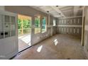 Unfinished living room area with drywall, windows, and a walk-out to the outside porch at 177 Millwood Dr, Clayton, NC 27527