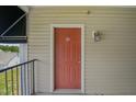 Condo front door with tan siding, overhead light, and black awning on the side with views of trees in the distance at 2521 Friedland Pl # 303, Raleigh, NC 27617