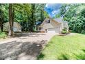 Paver driveway leading to a detached garage, set amidst a lush, wooded landscape at 26 Shadymont Dr, Pittsboro, NC 27312