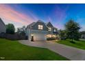 Beautifully landscaped two-story home with a two-car garage, lit up at dusk with a colorful evening sky at 315 Sugarpine Trl, Clayton, NC 27520