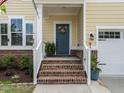 Inviting entrance featuring brick stairs, a blue front door adorned with a wreath, and potted plants at 3441 Jordan Shires Dr, New Hill, NC 27562
