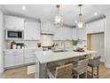 Bright kitchen featuring white cabinets, a central island with seating, and modern pendant lighting creating an inviting space at 361 Catheys Creek Cir, Wendell, NC 27591