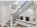 Stylish staircase with wood steps, black railing, built-in bench, and storage offering a modern and functional design at 361 Catheys Creek Cir, Wendell, NC 27591