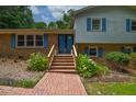 Charming brick home featuring a brick walkway, front stairs, and vibrant blue doors at 6308 Rolling Acres Drive, Gibsonville, NC 27249