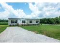 Gravel driveway leading to a beige manufactured home with a covered front porch at 100 Cottonwood Ct, Kenly, NC 27542