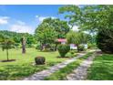 View of long driveway leading to single story home with well-manicured front yard and landscaping at 1007 Windward Hill Ct, Middlesex, NC 27557