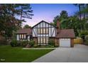 Charming Tudor-style home featuring a brick facade, white stucco, and a well-manicured front yard at 2020 Port Royal Rd, Raleigh, NC 27609