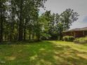 Lush green backyard with mature trees surrounding a single-story brick home at 4324 Garland Dr, Raleigh, NC 27606