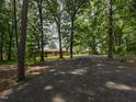 Gravel driveway leads to a single-story brick home surrounded by mature trees at 4324 Garland Dr, Raleigh, NC 27606