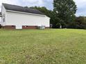 Spacious backyard showcasing a large, well-maintained lawn, brick foundation, and rear building exterior at 6 Boxley Dr, Wendell, NC 27591
