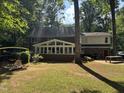 View of the back exterior, featuring a large sunroom and a spacious grassy yard at 7905 Breda Ct, Raleigh, NC 27606