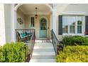 Covered front porch features a cozy bench, a light blue door with a wreath, and freshly painted stairs at 321 Wescott Ridge Dr, Holly Springs, NC 27540