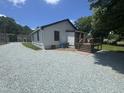 Rear view of a home with gravel driveway, showcasing a deck and side entrance at 3241 Rowena, Durham, NC 27703