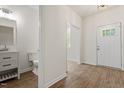 Hallway view with half bath and a white front door featuring decorative window panes and modern hardware at 1408 South St, Durham, NC 27707