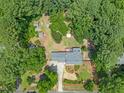 Aerial view of a wooded property with mature landscaping, a gravel driveway, and multiple outbuildings at 5209 Amsterdam Pl, Raleigh, NC 27606