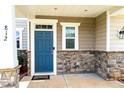 Close up of blue front door with stone trim and white accents and verdant landscaping at 812 Teal Lake Dr, Holly Springs, NC 27540