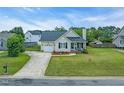 Exterior view of a charming one-story home with a well-maintained lawn and long driveway at 104 Roscommon Ln, Clayton, NC 27520