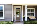 Charming front door adorned with a wreath, complemented by a welcome sign and cozy seating at 112 Star Valley Dr, Angier, NC 27501