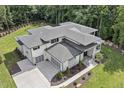 Aerial view showcasing the expansive roofline, three-car garage, and well-manicured landscaping of this modern home at 213 Westhampton Dr, Pittsboro, NC 27312