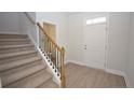 Bright foyer featuring stairs with carpet, a wooden handrail, and luxury vinyl plank flooring at 2937 Lemuel Black Rd, Bunnlevel, NC 28323