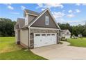 Side view of house showcasing attached garage, driveway, and view of a spacious landscaped yard at 75 Woodbark Cv # 10, Willow Springs, NC 27592